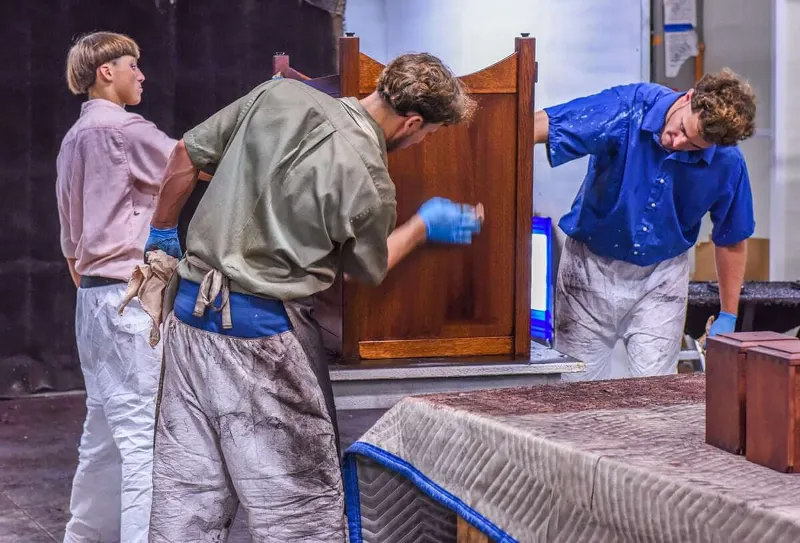 Amish woodworkers applying wood finish